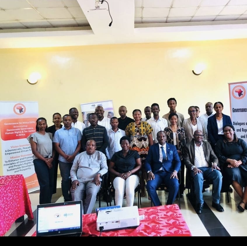 Group portrait of participants at a GFA governance dialogue, standing in front of GFA and partner banners.
